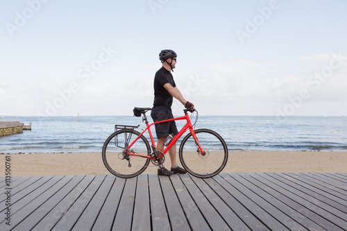 Man standing with bike looking at view of a Melbourne beach