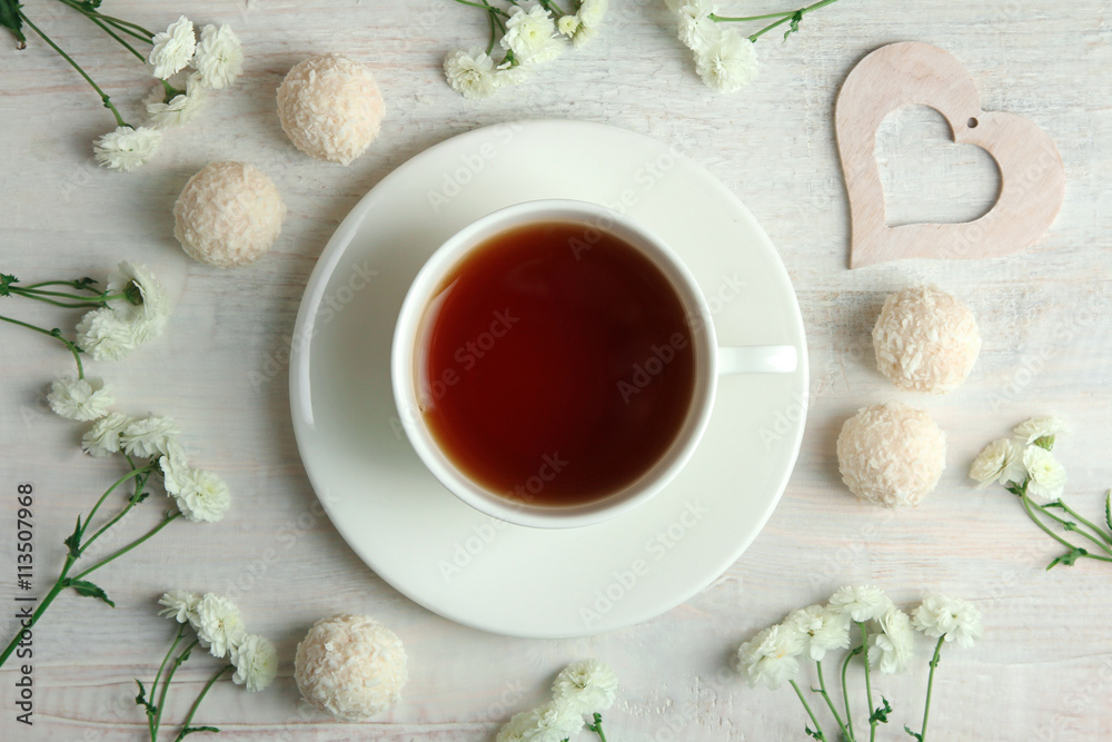 white decorative hearts with candy and flowers on white wooden background with Cup of tea white decorative hearts with candy and flowers on white wooden background with Cup of tea