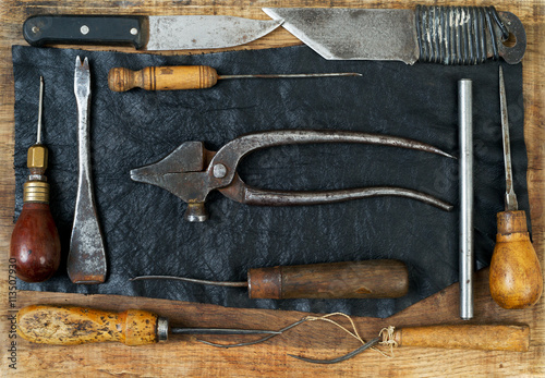 Leather craft tools on a wooden background. Craftmans work desk.