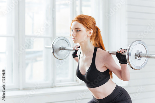 Close-up portrait of a woman doing squats with barbell