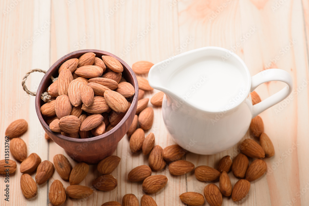 Almond milk in a jar with almond on a wooden table Almond milk in a jar with almond on a wooden table