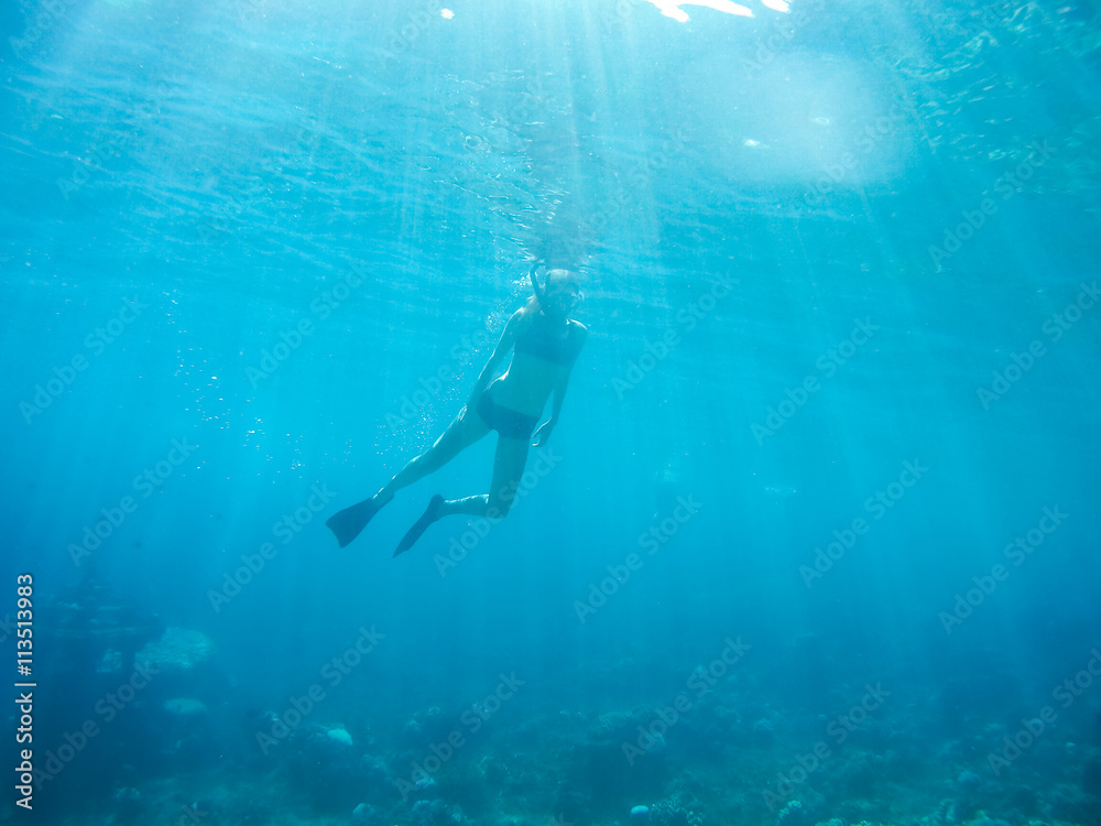 Obraz premium Underwater shot of the woman moving on the breath hold in the depth. Amed village, Bali, Indonesia