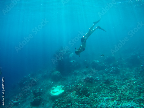 Underwater shot of the woman moving on the breath hold in the depth. Amed village, Bali, Indonesia