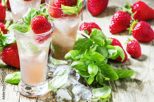 Pink cocktail with strawberry, basil, gin and ice, wood backgrou