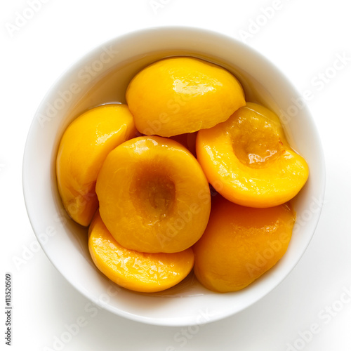 Canned peach halves in bowl isolated on white background. From a