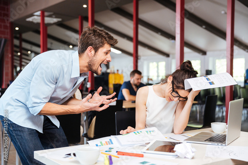 Mad crazy businessman arguing with sad stressed businesswoman in office