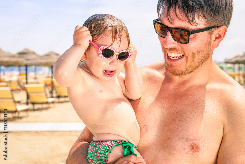 Father and toddler with bathing suit after swim on the beach - Young dad holding adorable baby outside resort on summer vacation day - Parent love concept and fun moment together Father and toddler with bathing suit after swim on the beach - Young dad holding adorable baby outside resort on summer vacation day - Parent love concept and fun moment together