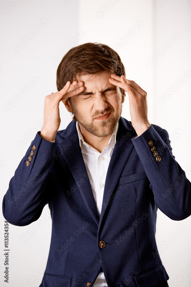 Young confused businessman standing near the office desk and hol Young confused businessman standing near the office desk and hol