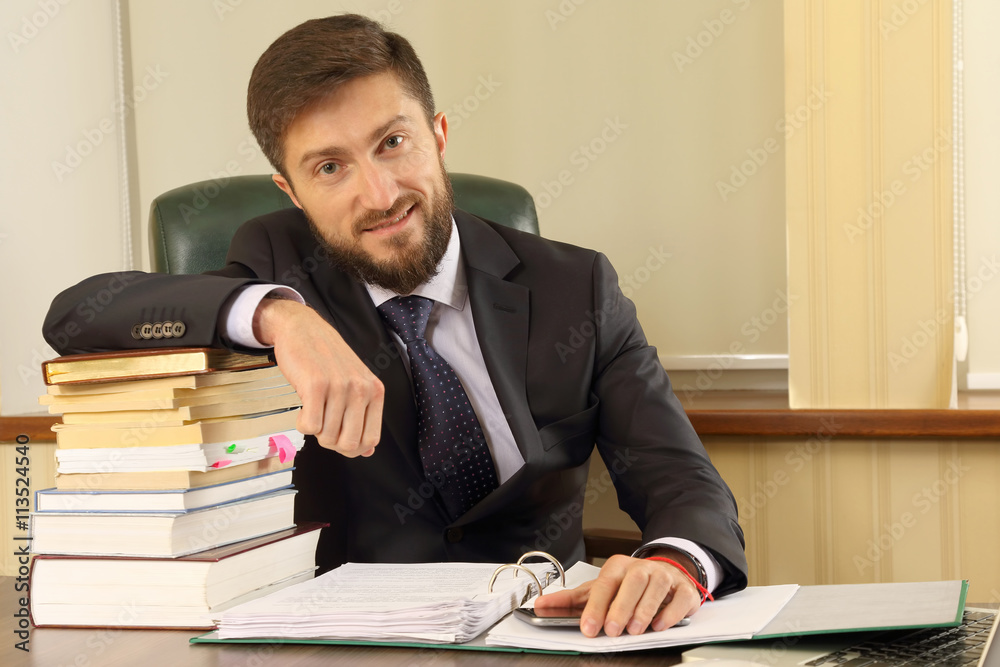 successful business man in the office with books and documents successful business man in the office with books and documents