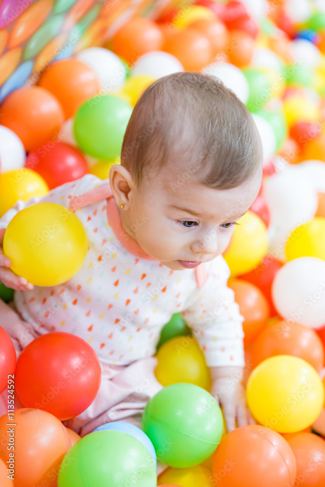 Obraz premium Beautiful baby girl playing with colorful balls