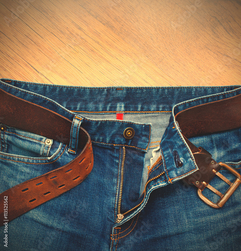 Aged blue jeans with a leather belt