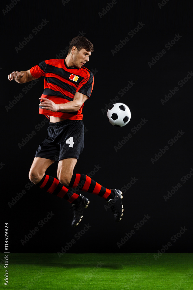 Soccer player kicking ball over black background