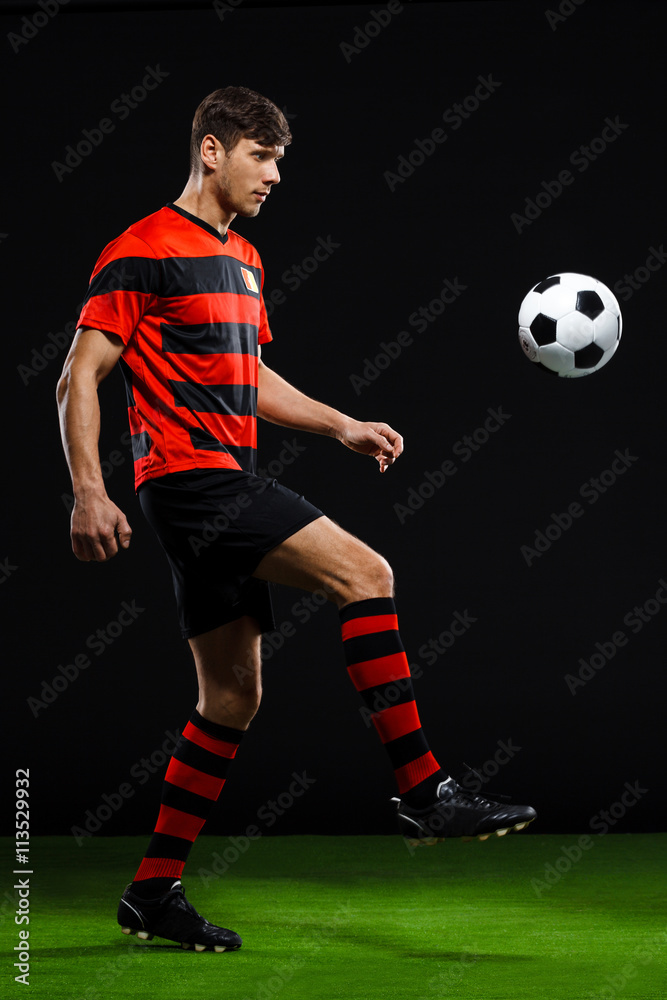 Soccer player kicking ball over black background