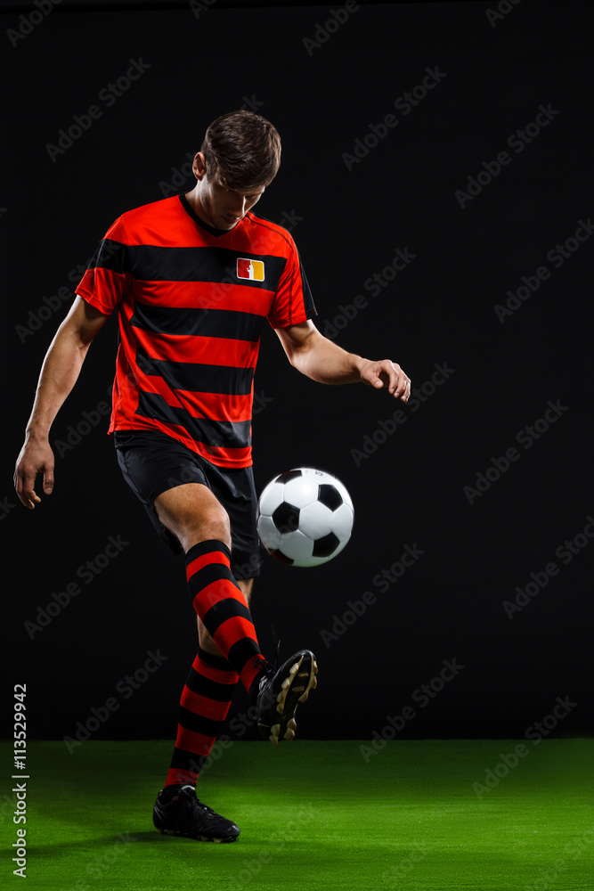 Soccer player kicking ball over black background