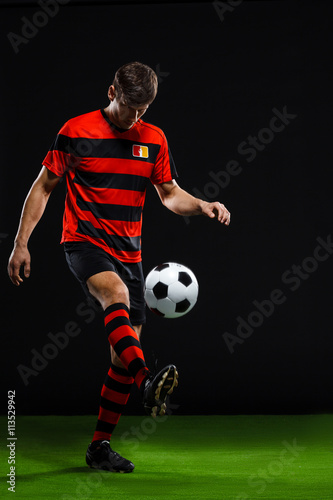 Soccer player kicking ball over black background © Cookie Studio