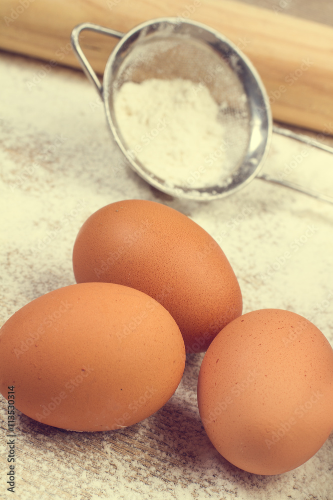Huevos de gallina y harina con colador de metal. Vista de cerca y de frente Huevos de gallina y harina con colador de metal. Vista de cerca y de frente