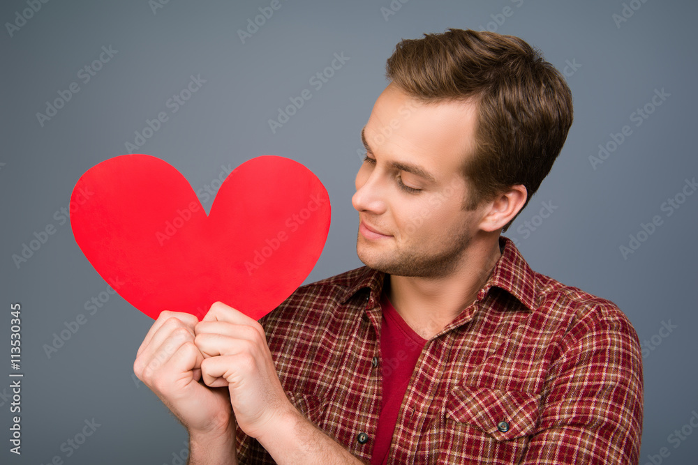 Handsome man looking at red paper heart in his hands Handsome man looking at red paper heart in his hands