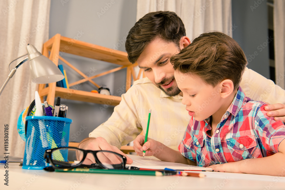 Happy family. Father and son doing homework together Happy family. Father and son doing homework together