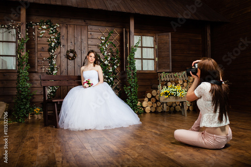 Young sexy woman photographer is taking pictures the bride in the studio photo