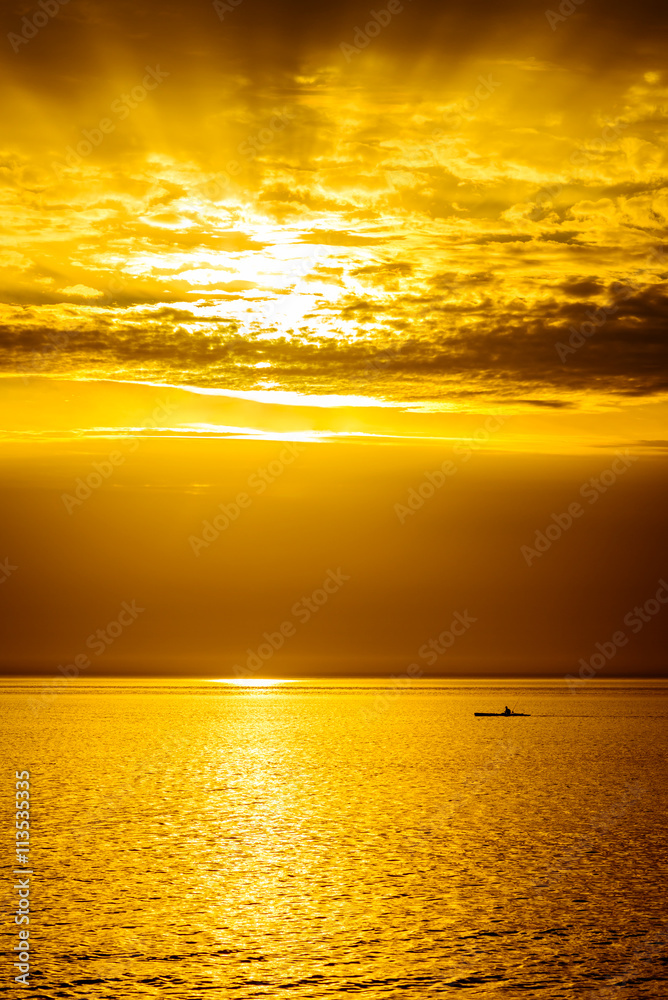 Fototapeta premium Silhouette of fisherman in the boat at sunset