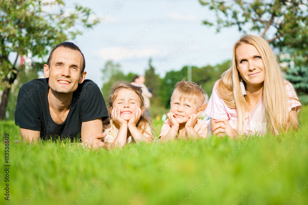 Portrait of happy parents with kids lying at the park