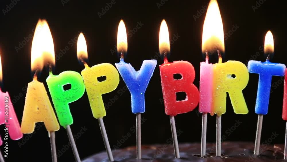 lighted candles on a happy birthday cake. candles with the words happy
