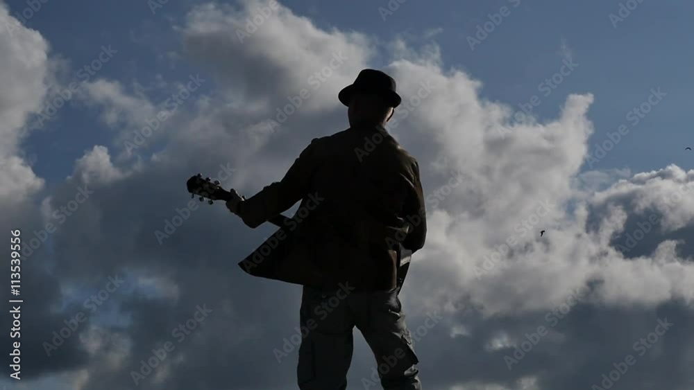 man with guitar back view against sun and clouds slow motion distancing follow focus man with guitar back view against sun and clouds slow motion distancing follow focus