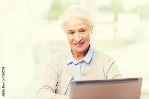 happy senior woman with laptop at home