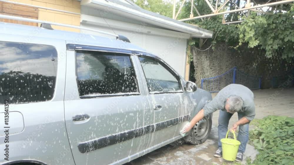 Man washing his silver car near the house. Man washing his silver car near the house.