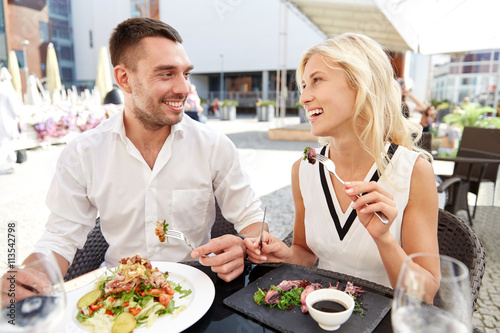 happy couple eating dinner at restaurant terrace