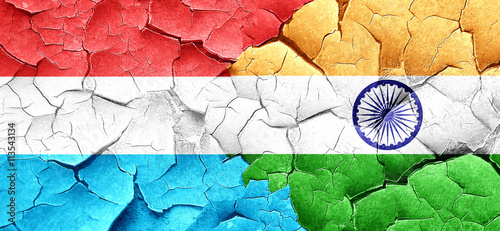 Luxembourg flag with India flag on a grunge cracked wall