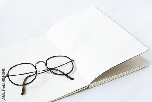 glasses on white page of opened notebook, white background