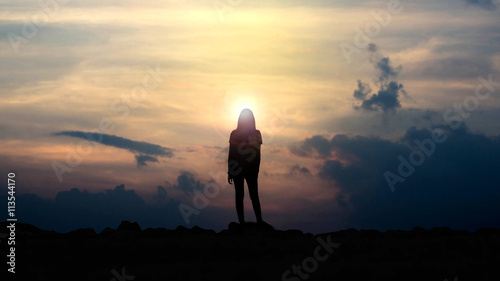 silhouette of a girl holding a camera watching the sunset.