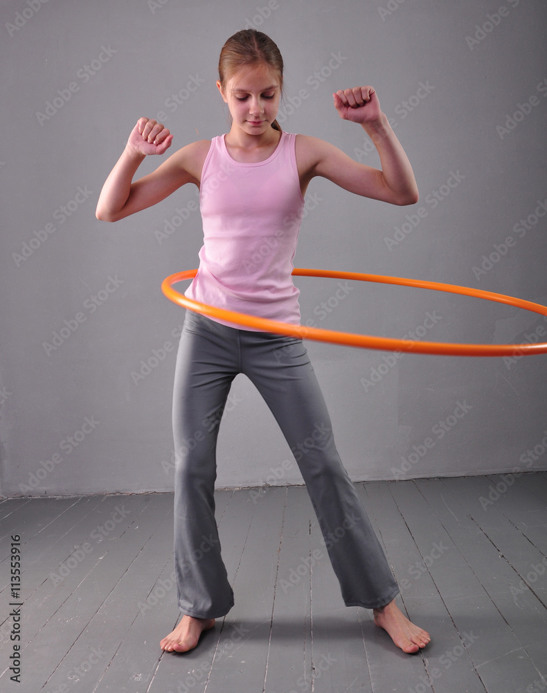 custom made wallpaper toronto digitalTeenage sportive girl is doing exercises with hula hoop on grey background. Having fun playing game . Sport healthy lifestyle concept. Sporty childhood. Teenager exercising with tool.