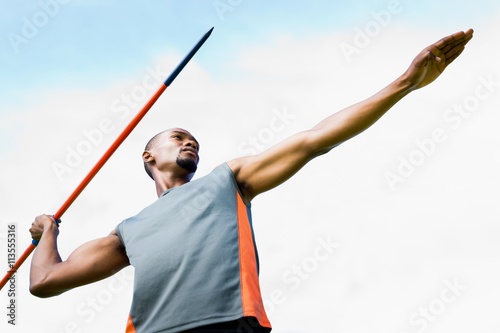 Low angle view of sportsman practising javelin throw  against blue sky with clouds 