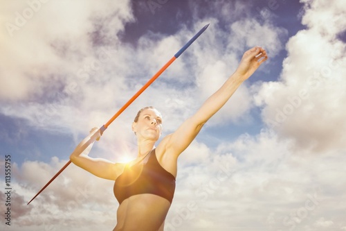 Low angle view of sportswoman is practising javelin throw  against blue sky with white clouds
