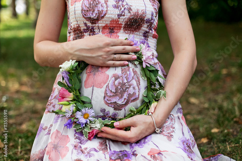 Pregnant girl presses a wreath to the stomach
