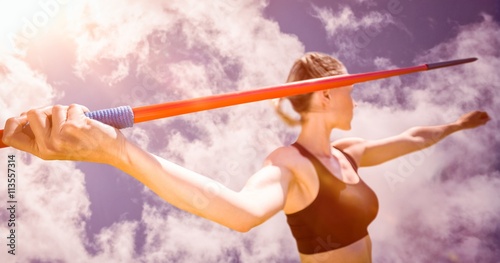 Close up of sportswoman hand holding a javelin against bright blue sky with clouds