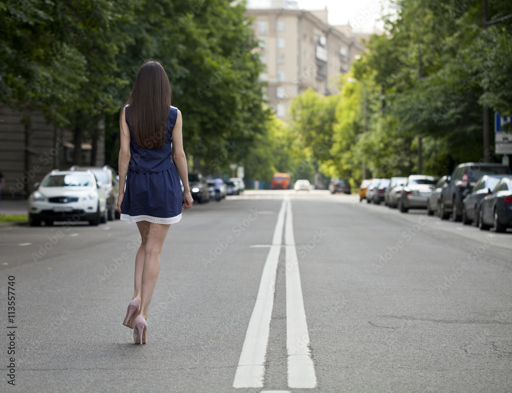 Young beautiful woman in a blue short dress walking on the road Young beautiful woman in a blue short dress walking on the road