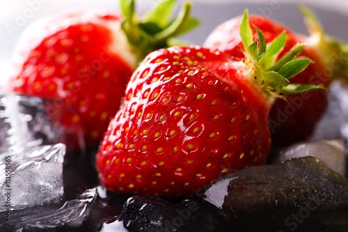 Three fresh strawberries on slate stone with ice