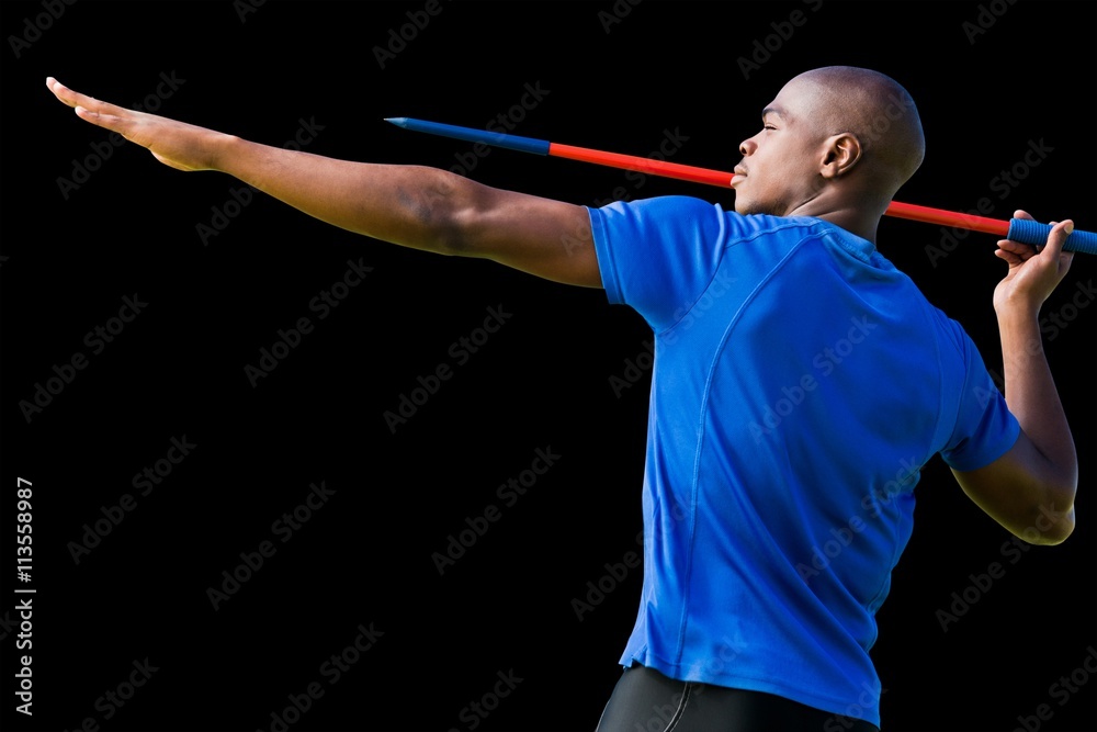 Profile view of sportsman practising javelin throw against black background Profile view of sportsman practising javelin throw against black background