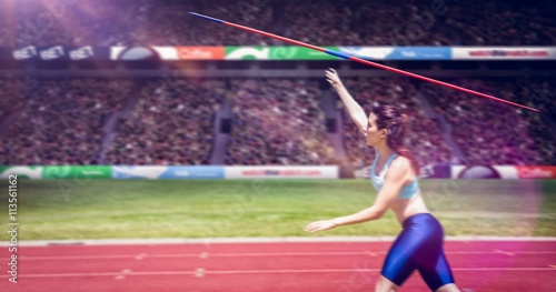 Profile view of sportswoman is practising javelin throw  against view of a stadium