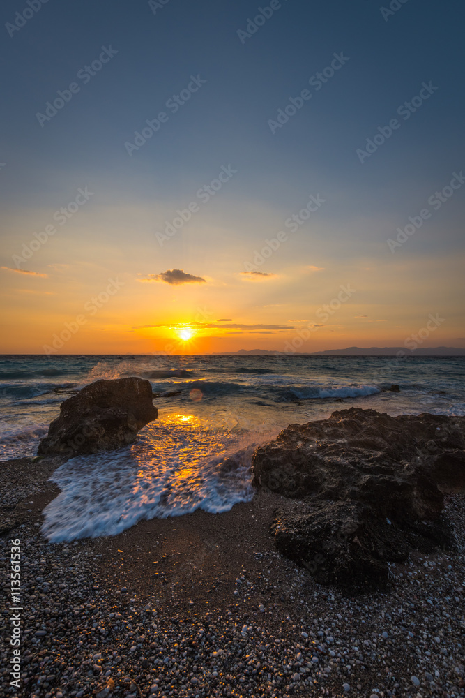Sunset in Rhodes, Greece with stones in the sea