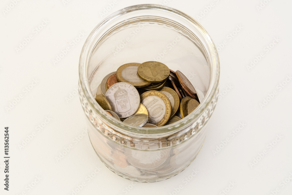 Transparent bank with coins of different metals of different denominations from different countries Transparent bank with coins of different metals of different denominations from different countries
