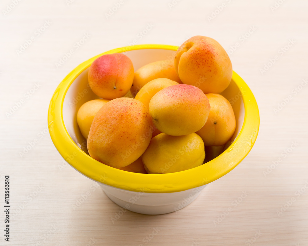The simple food composition with apricots in the bowl on the unique backing closeup The simple food composition with apricots in the bowl on the unique backing closeup