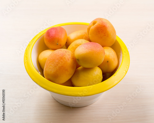 The simple food composition with apricots in the bowl on the unique backing closeup