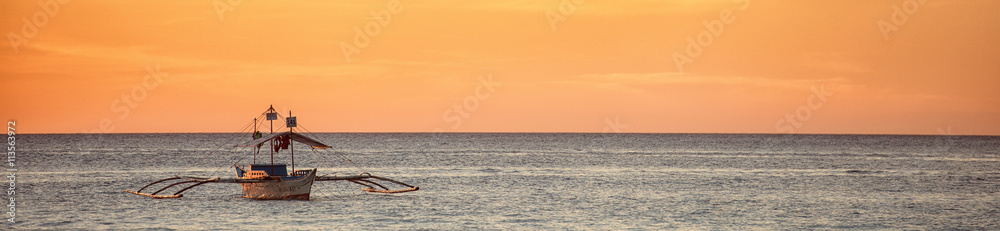 A wide view of the sea and a boat at a sunset in Boracay island