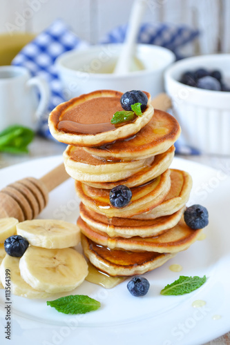 Small pancakes stacked with blueberries  banana and honey