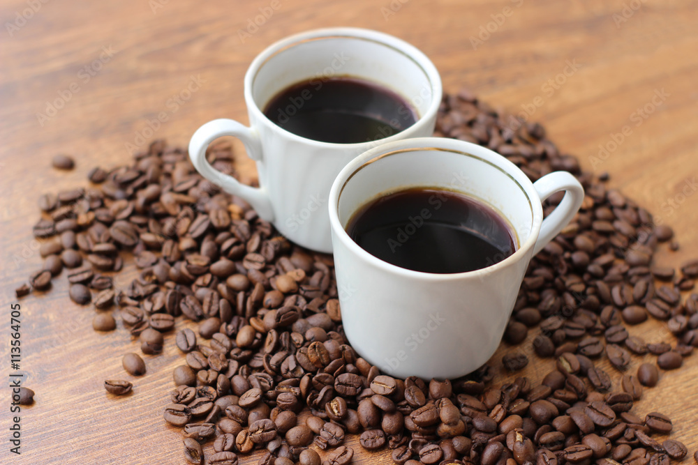 White Coffee mug with coffee beans on a wooden background closeup
