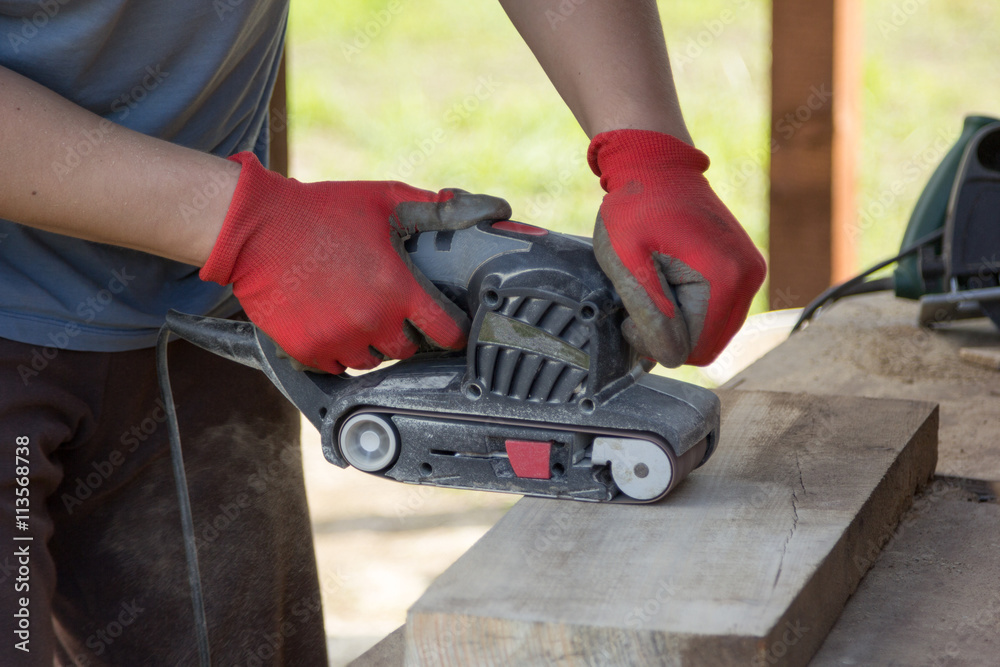 man grinds a board with sander man grinds a board with sander